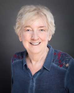 Author photo: Emma Dakin; smiling, white middle-aged female with short grayish-blonde hair wearing a dark blue button-down shirt.