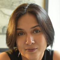 Headshot photo of Damyanti Biswas, female from India with short brown hair, wearing a black top, in front of a blurred framed print
