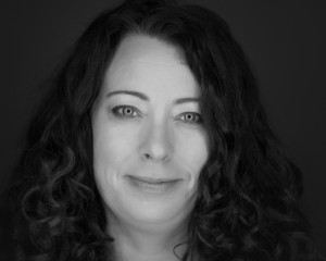 MHR Geer photo: black and white headshot photograph of a white woman with wavy dark-colored hair