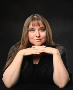 Photo of author K.M. Messina, a white female with brown hair, posed with her fingers intertwined under her chin