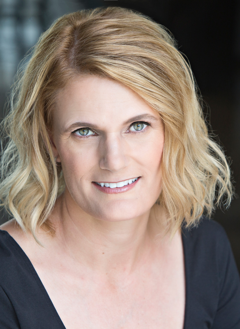 Author photo, headshot of smiling blonde female wearing a black top